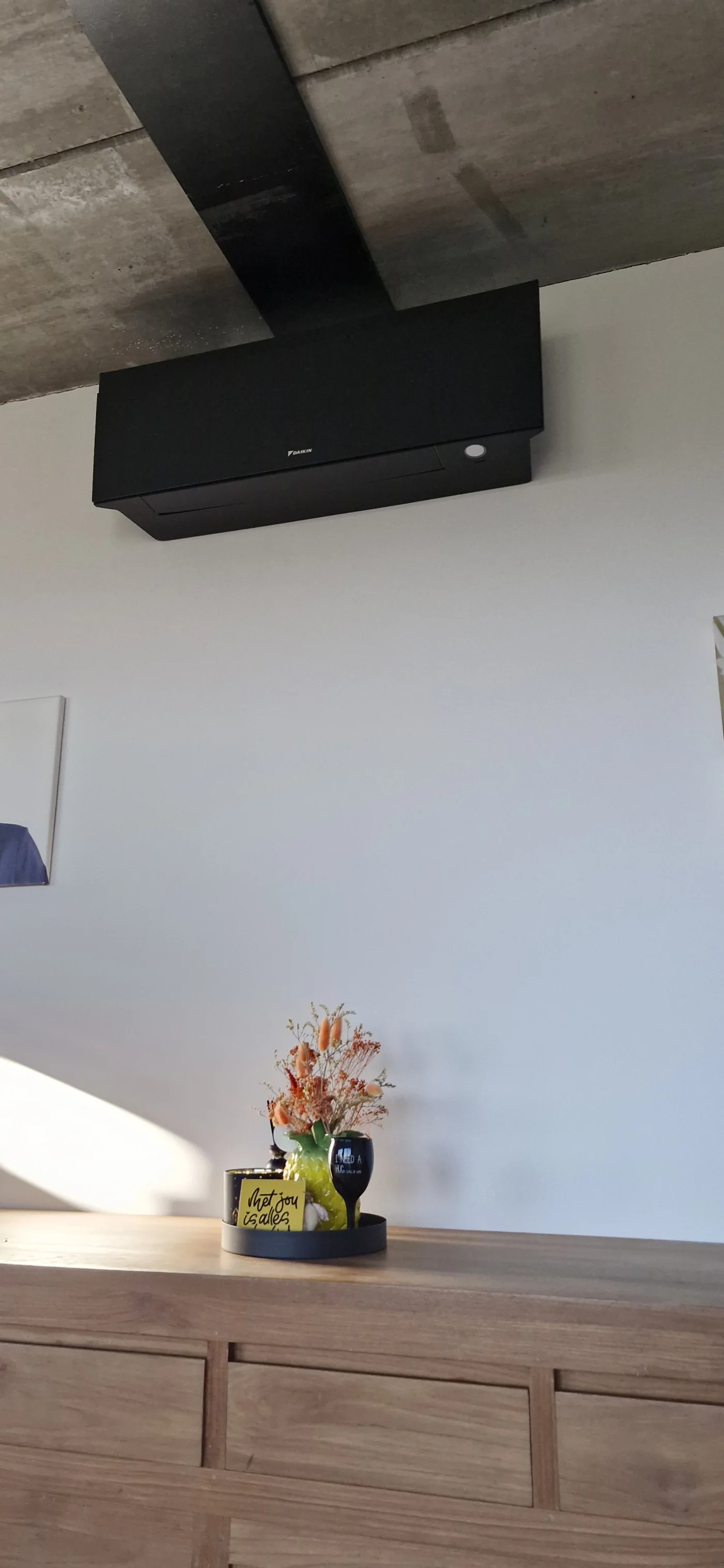 Zwarte airco-binnenunit in een interieur met hout, staal en beton