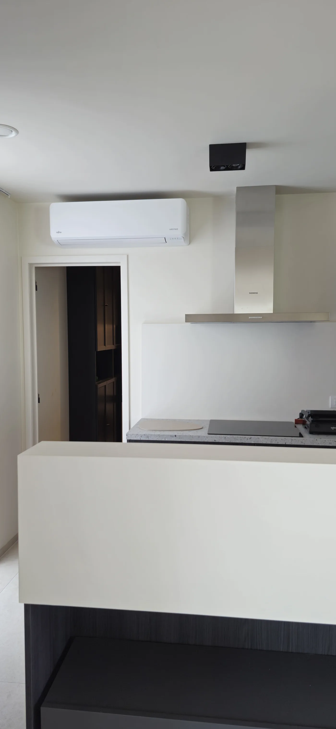 Witte Fujitsu-wandunit boven de deuropening in een lichte keuken